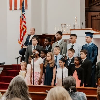 NECA students standing together in the church sanctuary during a school ceremony.